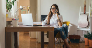 Mulher ao telefone, trabalhando em casa, exercendo o teletrabalho com conforto e organização